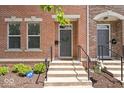 Brick townhome features entry door with concrete steps, black railings and manicured shrubs at 2405 N Park Ave, Indianapolis, IN 46205