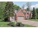 Charming red brick home with a three-car garage, lush greenery, and a beautifully landscaped yard at 2884 Brook Vista Dr, Carmel, IN 46032