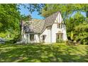 Charming Tudor-style home featuring a unique multi-colored roof and lush, green lawn at 4302 Kessler Blvd N Dr, Indianapolis, IN 46220