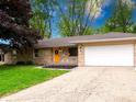 A charming single-story stone home with a bright yellow front door and an attached two car garage at 444 Buffalo Dr, Indianapolis, IN 46217