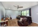 Cozy living room with wood floors, a ceiling fan, a plush leather sofa, and natural light from a window at 4716 E 33Rd St, Indianapolis, IN 46218