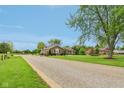 Charming home with long stone driveway, mature trees and professional landscaping on a sunny day at 4732 Ferguson Rd, Indianapolis, IN 46239