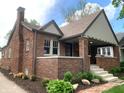 Quaint brick house with a cozy front porch, well-kept landscaping, inviting entrance, and architectural charm at 5912 Evanston Ave, Indianapolis, IN 46220