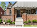 Inviting brick home showcasing a covered porch, decorative details, manicured bushes, and concrete steps to entry at 5912 Evanston Ave, Indianapolis, IN 46220