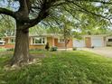 Well maintained brick home with green grass and mature trees providing shade at 6335 Linden Dr, Indianapolis, IN 46227