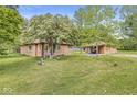 A charming brick house and patio, surrounded by green grass and mature trees under a blue sky at 6401 N Oakland Ave, Indianapolis, IN 46220