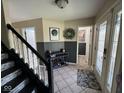 Inviting foyer with tile flooring, decorative accents, and staircase with black railing at 8507 Promontory Rd, Indianapolis, IN 46236