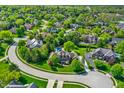 Aerial view of a residential neighborhood showcasing lush green trees, manicured lawns, and a private pool at 13827 Driftwood Dr, Carmel, IN 46033