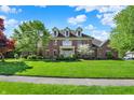 Stately brick home featuring dormer windows and a manicured lawn with mature trees at 13827 Driftwood Dr, Carmel, IN 46033