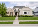 Charming two-story home with stone and brick, complemented by a lush green lawn and inviting walkway at 14003 Grannan Ln, Carmel, IN 46074