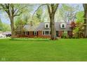 Well-maintained brick home with lush lawn, mature trees, and dormer windows at 1409 Alimingo Dr, Indianapolis, IN 46260