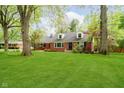 Brick home boasts mature trees, green lawn, dormer windows, and a welcoming front entrance at 1409 Alimingo Dr, Indianapolis, IN 46260