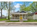 Charming home with a large front porch and vibrant yellow door adding curb appeal at 1421 Laurel St, Indianapolis, IN 46203