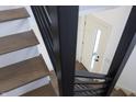 Modern staircase featuring hardwood treads, white risers, and black metal railings and a view of a door at 1525 Marlowe Ave, Indianapolis, IN 46201