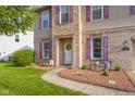 Inviting home entrance features a classic white door, brick accents, and colorful landscaping at 1969 Westminster Pl, Columbus, IN 47201