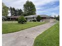 Attractive one-story home with a concrete driveway, manicured lawn, and mature trees at 2927 E 8Th St, Anderson, IN 46012