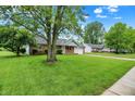 Brick home nestled on a green lot with mature trees, featuring an attached garage and a paved driveway at 374 S Baldwin St, Bargersville, IN 46106