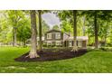 Well-maintained home featuring manicured lawn, mulch beds, and mature trees at 411 Woodland W Dr, Greenfield, IN 46140