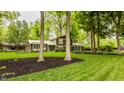 Inviting home surrounded by a lush lawn, mature trees, and landscaped flower beds at 411 Woodland W Dr, Greenfield, IN 46140