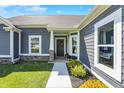 Inviting home entrance with gray siding, a decorated front door, and landscaped greenery at 49 Manchester Dr, Trafalgar, IN 46181