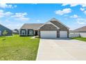 Beautiful single-story home with gray siding, stone details, and a spacious driveway under a blue sky at 49 Manchester Dr, Trafalgar, IN 46181