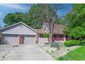 A view of the home with a spacious driveway and attached garage, complemented by neat landscaping and colorful shutters at 6334 Teak Ct, Indianapolis, IN 46217