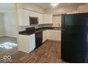 Modern kitchen featuring white cabinets, black appliances, and stylish flooring, perfect for cooking at 706 Alexander St, Greenwood, IN 46143