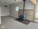 Inviting living area featuring wood-burning stove, stone surround, new carpet, and a ceiling fan at 706 Alexander St, Greenwood, IN 46143