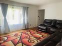 Bright living room featuring a comfortable leather sectional sofa, hardwood floors, and sheer curtains at 7844 Partridge Rd, Southport, IN 46227