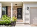 Close-up of front porch featuring brick accents, security system sign, and well-maintained landscaping at 9915 Wellsford Cir, Indianapolis, IN 46236