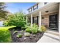 Inviting covered front porch with brick accents, stylish door, and lush landscaping at 9915 Wellsford Cir, Indianapolis, IN 46236