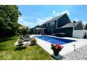 An in-ground pool with a hot tub surrounded by comfortable lounge furniture sits in a well-maintained backyard at 1050 Windsor Estates Ct, Westfield, IN 46074