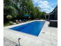 An in-ground pool surrounded by lounge chairs sits alongside a hot tub in this backyard retreat at 1050 Windsor Estates Ct, Westfield, IN 46074