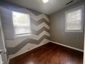 Bedroom showcasing a chevron-patterned accent wall, hardwood flooring, and a large window at 1605 S Whittier Pl, Indianapolis, IN 46203