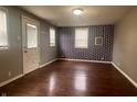 Bright living room features wood flooring, neutral paint, two windows with blinds, and a back entry door at 1605 S Whittier Pl, Indianapolis, IN 46203
