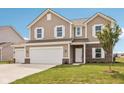 Beautiful two-story home boasts a three-car garage, brick accents, and a well-maintained lawn at 1614 N Clearwater Dr, Greenfield, IN 46140