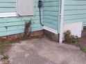 Shows the exterior of a home with turquoise wood siding, a concrete foundation, and overgrown landscaping at 2134 Dr Andrew J Brown Ave, Indianapolis, IN 46202