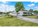 A single-story home with a detached garage featuring a well-maintained lawn and driveway at 2726 Dawson St, Indianapolis, IN 46203