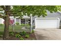 Inviting home exterior with a white garage door, picket fence, and lush greenery at 3602 Bay Rd S Dr, Indianapolis, IN 46240