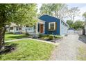 Quaint blue home showcasing a well-maintained front yard, a covered porch, and a stone driveway at 5119 Ralston Ave, Indianapolis, IN 46205