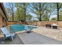 Outdoor pool and patio area surrounded by a wooden fence and mature trees. Includes chairs and gas grill at 5312 Larita Ln, Anderson, IN 46017