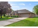 Lovely single-story brick home with an attached two-car garage, showcasing a well-maintained lawn and driveway at 5601 W Sun Point Dr, Muncie, IN 47304