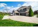 Angle view of a three-car garage, spacious driveway, and partial view of the home's exterior at 5990 Hollow Ct, Bargersville, IN 46106