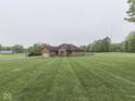 Sprawling brick home on a large lot featuring manicured lawns and mature trees at 6494 N Baltimore Rd, Monrovia, IN 46157