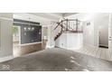 Spacious living room featuring an elegant staircase, modern chandelier, and neutral carpeting at 6818 Bluffridge Dr, Indianapolis, IN 46278