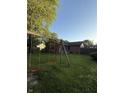 Spacious backyard with mature trees and lush green lawn, featuring a classic wooden swing set at 7627 Venetian Way, Indianapolis, IN 46217