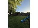 Expansive backyard featuring mature trees, green lawn, and a slide for outdoor fun at 7627 Venetian Way, Indianapolis, IN 46217