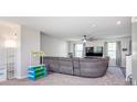 Carpeted living room showcasing a grey couch, fan, and entertainment center at 830 Black Rock Cir, Lebanon, IN 46052