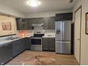 Kitchen featuring stainless steel appliances, marbled countertops, and dark cabinets on wood-look floors at 11506 Hidden Bay, Indianapolis, IN 46236