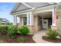 Welcoming covered front porch with decorative plants, columns, and an American flag at 16270 Northwind Ct, Westfield, IN 46074